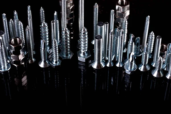 A fantastic city made of bolts, nuts, screws and self-cuts on a black background with reflection. Iron city