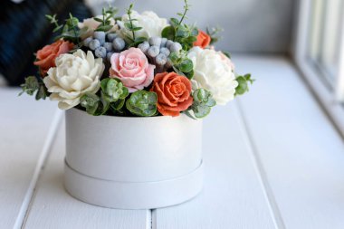 Hediye silindirik karton bir kutuda güzel, parlak gül çiçekleri. Bir buket sabun çiçeği.