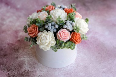 Hediye silindirik karton bir kutuda güzel, parlak gül çiçekleri. Bir buket sabun çiçeği.