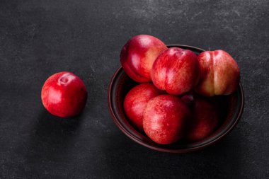 Lezzetli tatlı şeftaliler ya da kahverengi bir kasede koyu beton bir arka planda nektarinler.