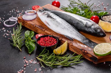 Taze balık deniz kabuğu ve yemek pişirmek için malzemeler. Koyu bir masada baharat ve bitkilerle çiğ balık deniz kabuğu.