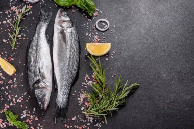 Taze balık deniz kabuğu ve yemek pişirmek için malzemeler. Koyu bir masada baharat ve bitkilerle çiğ balık deniz kabuğu.