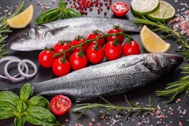 Taze balık deniz kabuğu ve yemek pişirmek için malzemeler. Koyu bir masada baharat ve bitkilerle çiğ balık deniz kabuğu.