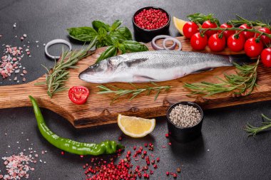 Taze balık deniz kabuğu ve yemek pişirmek için malzemeler. Koyu bir masada baharat ve bitkilerle çiğ balık deniz kabuğu.