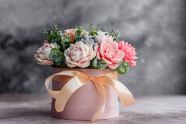 Hediye silindirik karton bir kutuda güzel, parlak gül çiçekleri. Bir buket sabun çiçeği.