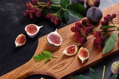 Karanlık bir arka planda taze incir ve böğürtlen. Böğürtlen ve meyve topluyorum.