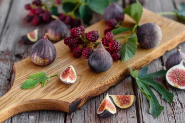 Karanlık bir arka planda taze incir ve böğürtlen. Böğürtlen ve meyve topluyorum.