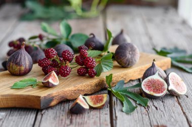 Karanlık bir arka planda taze incir ve böğürtlen. Böğürtlen ve meyve topluyorum.