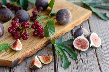 Karanlık bir arka planda taze incir ve böğürtlen. Böğürtlen ve meyve topluyorum.