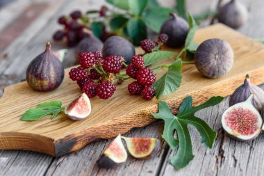 Karanlık bir arka planda taze incir ve böğürtlen. Böğürtlen ve meyve topluyorum.