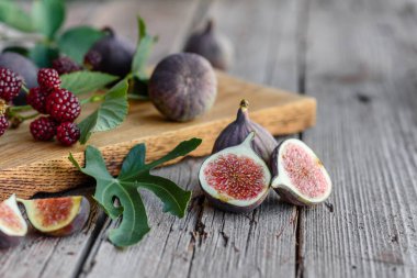 Karanlık bir arka planda taze incir ve böğürtlen. Böğürtlen ve meyve topluyorum.