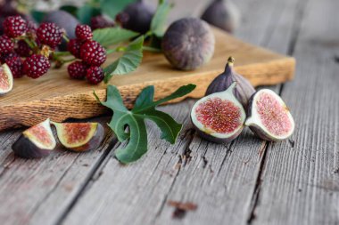 Karanlık bir arka planda taze incir ve böğürtlen. Böğürtlen ve meyve topluyorum.