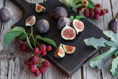 Karanlık bir arka planda taze incir ve böğürtlen. Böğürtlen ve meyve topluyorum.