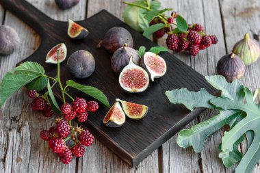 Karanlık bir arka planda taze incir ve böğürtlen. Böğürtlen ve meyve topluyorum.