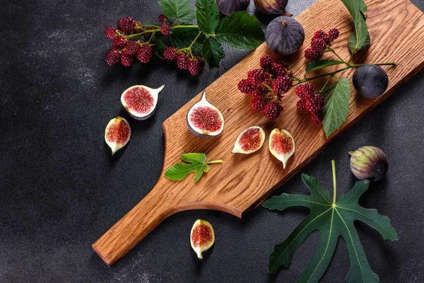 Fresh juicy figs and blackberries on a dark background. Harvesting berries and fruits