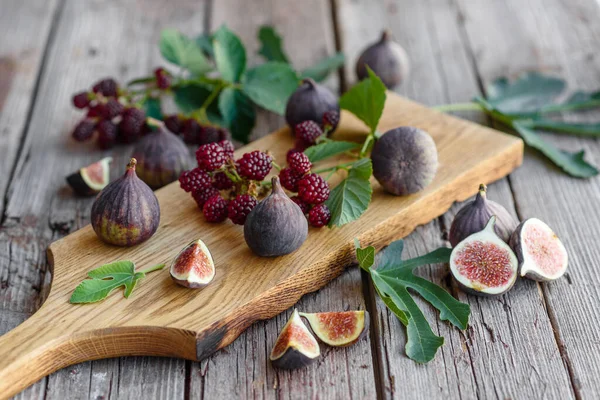 Fresh juicy figs and blackberries on a dark background. Harvesting berries and fruits