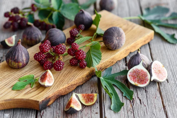 Fresh juicy figs and blackberries on a dark background. Harvesting berries and fruits