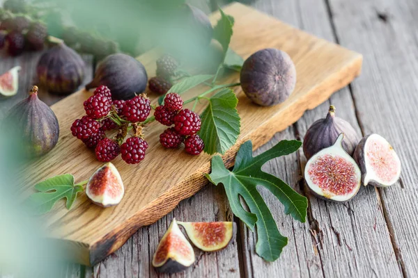 Karanlık bir arka planda taze incir ve böğürtlen. Böğürtlen ve meyve topluyorum.