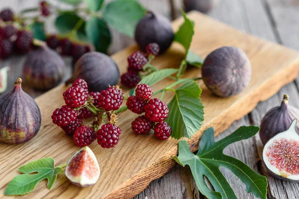 Fresh juicy figs and blackberries on a dark background. Harvesting berries and fruits