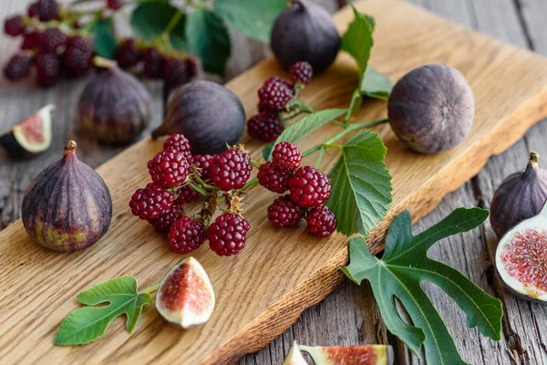 Fresh juicy figs and blackberries on a dark background. Harvesting berries and fruits