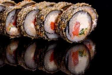 Karanlık bir arka planda taze, lezzetli suşi ruloları. Japon mutfağının elementleri