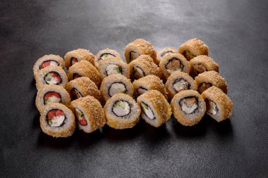 Karanlık bir arka planda taze, lezzetli suşi ruloları. Japon mutfağının elementleri