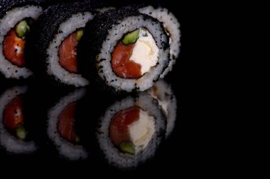 Karanlık bir arka planda taze, lezzetli suşi ruloları. Japon mutfağının elementleri