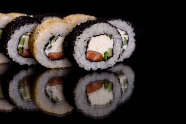 Karanlık bir arka planda taze, lezzetli suşi ruloları. Japon mutfağının elementleri