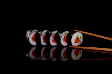 Karanlık bir arka planda taze, lezzetli suşi ruloları. Japon mutfağının elementleri