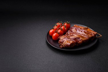 Lezzetli tütsülenmiş ya da ızgara pirzola, zeytin, baharat ve otlu koyu beton arka planda.