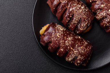 Meyve dolu lezzetli çikolatalı kekler ve koyu beton arka planda seramik bir tabağa serpiştirilmiş şekerler.