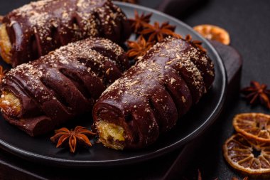 Meyve dolu lezzetli çikolatalı kekler ve koyu beton arka planda seramik bir tabağa serpiştirilmiş şekerler.