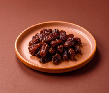 Seramik tabakta kurutulmuş hurmalar, ramazan tabağı için Arapça yiyecekler. Kurumuş tarihler tasarımın için bir yemek arkaplanı olarak kullanılacak..