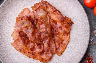 Fried pork bacon slices or strips as a breakfast ingredient. Fried bacon as a food background for your design