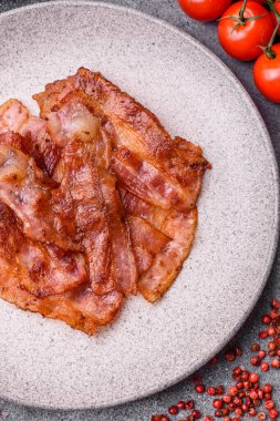 Fried pork bacon slices or strips as a breakfast ingredient. Fried bacon as a food background for your design
