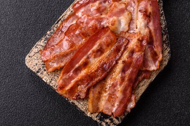 Fried pork bacon slices or strips as a breakfast ingredient. Fried bacon as a food background for your design