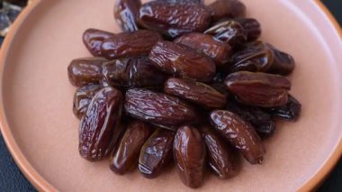 Seramik tabakta kurutulmuş hurmalar, ramazan tabağı için Arapça yiyecekler. Kurumuş tarihler tasarımın için bir yemek arkaplanı olarak kullanılacak..