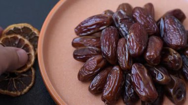 Seramik tabakta kurutulmuş hurmalar, ramazan tabağı için Arapça yiyecekler. Kurumuş tarihler tasarımın için bir yemek arkaplanı olarak kullanılacak..