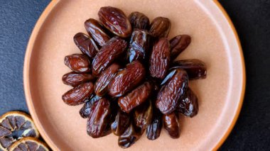 Seramik tabakta kurutulmuş hurmalar, ramazan tabağı için Arapça yiyecekler. Kurumuş tarihler tasarımın için bir yemek arkaplanı olarak kullanılacak..