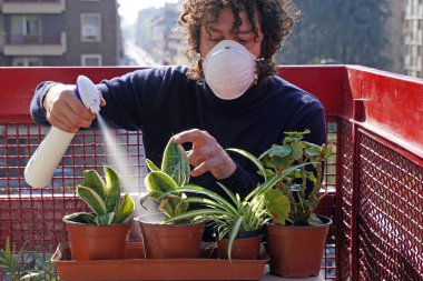 İş adamı çocuk, Covid-19 Coronavirus karantina evinde maskeyle bahçeyle uğraşıyor. Salgın hastalıklı bir yaşam tarzı.