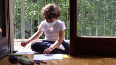 Genç çocuk balkonda resim çiziyor.