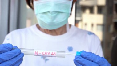 Maskeli doktor laboratuvarda şırınga tutuyor.