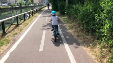 Parkta bisiklet süren küçük bir çocuk.