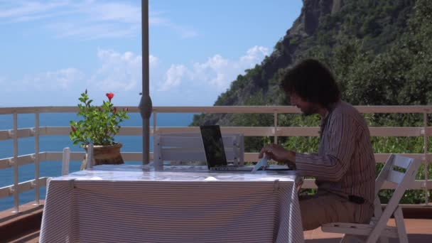 Homme Bouclé Travaillant Avec Ordinateur Portable Sur Balcon Avec Fond — Video