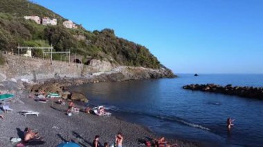 İnsanlar İtalyan sahillerinde güneşleniyor ve yüzüyor.