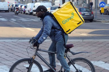 Milan, İtalya - 15 Şubat 2019: Bisikletle Glovo teslimatı - iş yerinde zenci çocuk