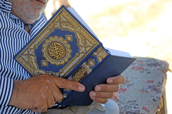man holding koran with bible