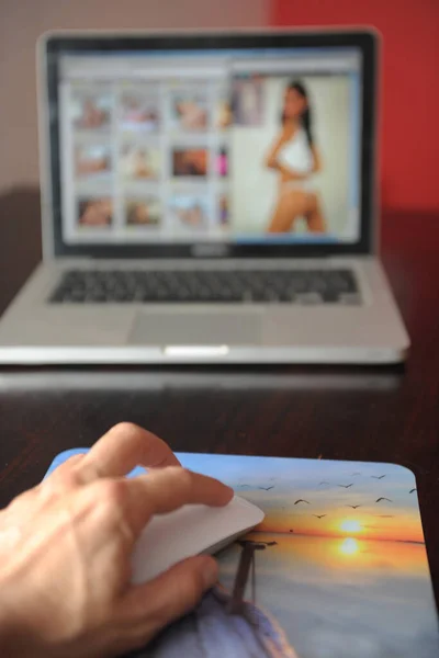 hand on pc mouse and laptop screen with women in the background, lingerie, bikini
