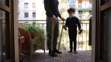 Çocuklu bir adam balkonda spor egzersizleri yapıyor.