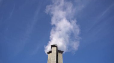 Şömineden çıkan duman, ısıtma. yüzen duman. Mavi gökyüzünün arka planında bir ev bacasından çıkıyor - kirlilik ve ince toz